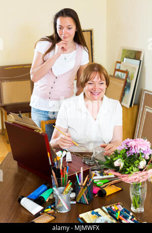 Smiling experienced senior teacher gives advice to the beginner. Focus on the mature woman Stock Photo