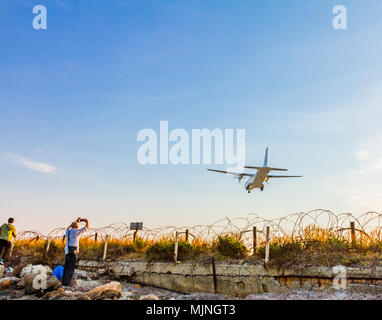 People photographing a turboprop air plane landing at Larnaca International Airport on a sunny afternoon Stock Photo