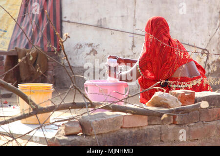 Indian woman in beautiful traditional sari doing laundry by hand in rural Rajasthan (Dahmi Kalan region near Jaipur). Stock Photo