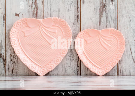 Colorful porcelain plates with heart shape on white wooden background Stock Photo