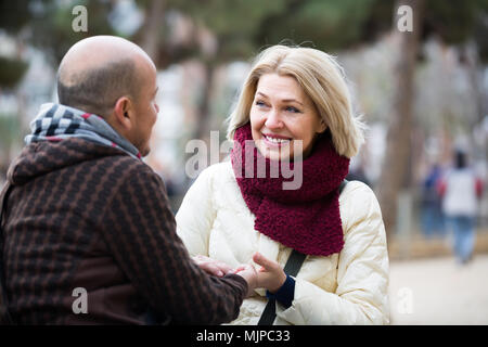 Portrait of happy smiling mature couple having interesting conversation outdoors Stock Photo