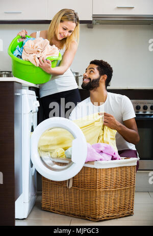 Happy young mixed spouses doing regular laundry and smiling Stock Photo