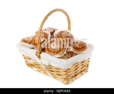 Wicker basket filled with cinnamon rolls in tins of greaseproof paper isolated on white. Stock Photo