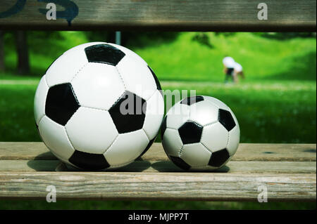 two soccer balls on a parkbench in spring Stock Photo
