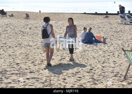 Boscombe, Bournemouth, Dorset, UK, 6th May 2018, Weather: Morning sunshine on the south coast on what could be the hottest Mayday bank holiday weekend on record. Two women carrying sunbeds onto the beach.