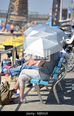 Boscombe, Bournemouth, Dorset, UK, 6th May 2018, Weather: Morning sunshine on the south coast on what could be the hottest Mayday bank holiday weekend on record. People sitting on the promenade under silver sun umbrellas.