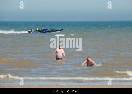 Greatstone, Kent, UK. 6th May 2018. Brilliant sunny day on the beach with lots of families making the most of the Bank holiday weather. A speedboat goes by while two male swimmers swim in the sea. Photo Credit: Paul Lawrenson /Alamy Live News Stock Photo