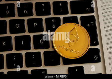 Ethereum cryptocurrency coin over a laptop's keyboard on a overhead view Stock Photo