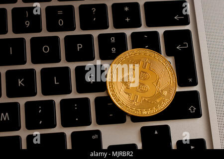 Bitcoin cryptocurrency coin over a laptop's keyboard Stock Photo