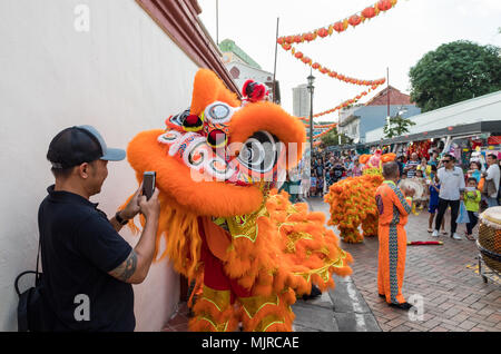 Singapore - March 24, 2018: A man takes a photo up close of performers in traditional costume performing the Chinese lion dance, Chinatown Stock Photo