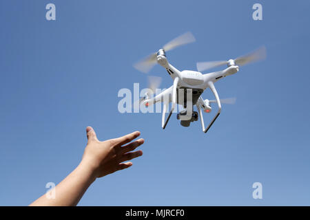 Hand catching drone aircraft in blue sky background, camera operator concept of aerial photography Stock Photo