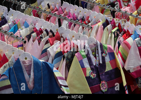 Colorful children's clothing hanging on racks in front of a shop in Seoul, South Korea. These little jackets were sewn from many colored cloths. Stock Photo