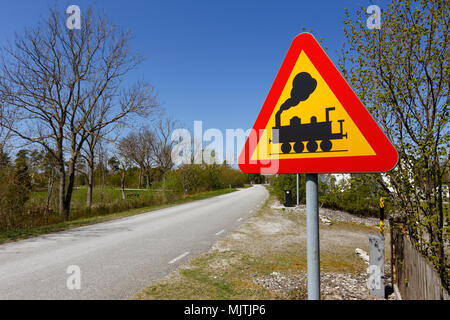 Swedish road sign Level crossing without gates ahead at the side of a narrow road. Stock Photo