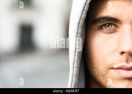 Good looking young man with blue eyes in the street wearing hooded jacket Stock Photo