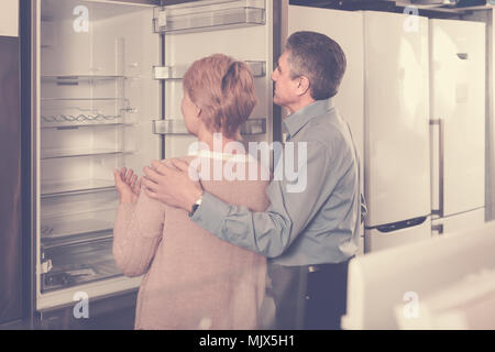 Mature couple  chooses refrigerator in store of household appliances Stock Photo