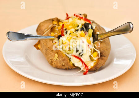 Baked kumpir potato stuffed with the cheese, sausage, olives, peppers and corn Stock Photo