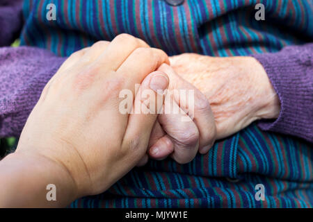 Close up picture of elderly disabled female hands with loving caregiver Stock Photo