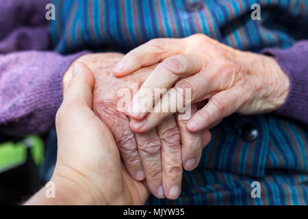 Close up picture of elderly disabled female hands with loving caregiver Stock Photo