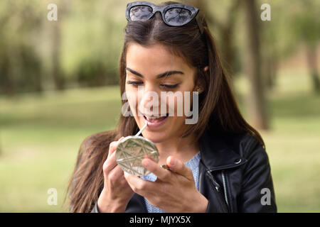 Portrait of young woman making up herself in urban background Stock Photo