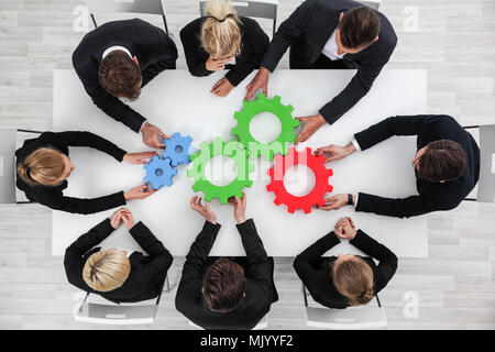 Business problem solution, mechanism of business, teamwork concept, business team sitting around white table with cogs Stock Photo