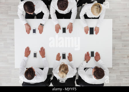 Business people not using smartphones sitting around white table Stock Photo