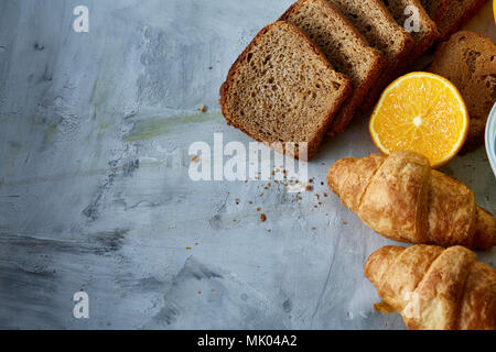 Breakfast served with croissants, oranges, apples and bread slices on white kitchen table, top view, close-up, selective focus. Perfect vegetarian sna Stock Photo