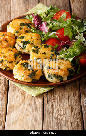 Fried meat balls with spinach and a salad of fresh vegetables close-up on a plate. vertical Stock Photo