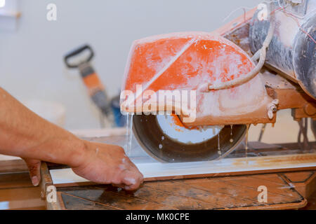 Manual cutting of ceramic tiles on a special machine for cutting tiles. Stock Photo