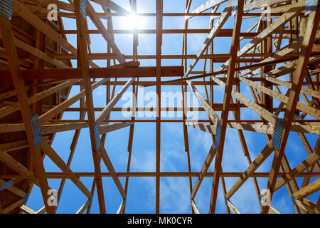 New construction home framing against blue sky, closeup of ceiling frame. Stock Photo