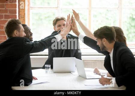 Happy work team giving high five after closing business deal Stock Photo