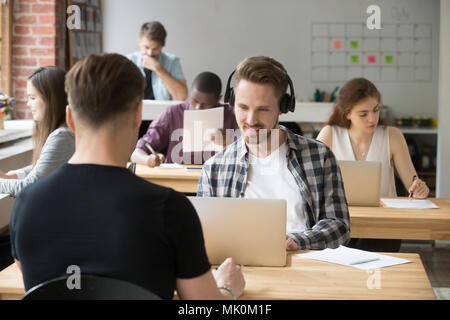 Male worker listening to music working on laptop Stock Photo
