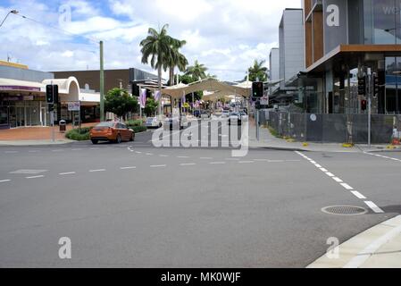 Central Business District, Coffs Harbour, Australia. Moving traffic on street. Image has cars, vehicles, shops, offices, buildings, footpath, trees Stock Photo