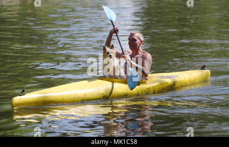 Veron Pimm, accompanied by his canine passenger Bibi, kayaks along the River Thames close to Boulter's Lock in Maidenhead Riverside, Berkshire. Sun worshippers are set to sizzle in the spring heatwave, with Bank Holiday Monday forecast to be the hottest since records began. Stock Photo