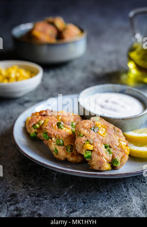 Healthy tuna Fish cakes with green peas, corn and scallion served with sour cream dip Stock Photo