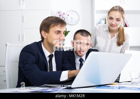 Three smiling coworkers working on computers together in company office Stock Photo