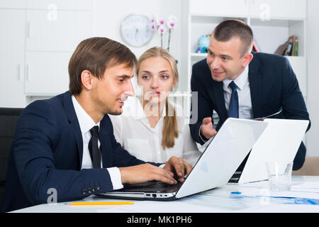 portrait of three friendly colleagues with laptops at the table in office . Selective focus Stock Photo