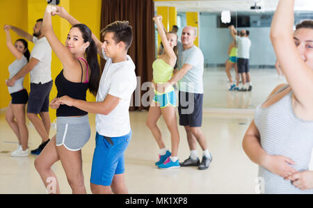 Group of smiling people practicing salsa together in dance studio Stock Photo