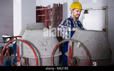 Smiling male worker using concrete mixer for construction work at workplace Stock Photo