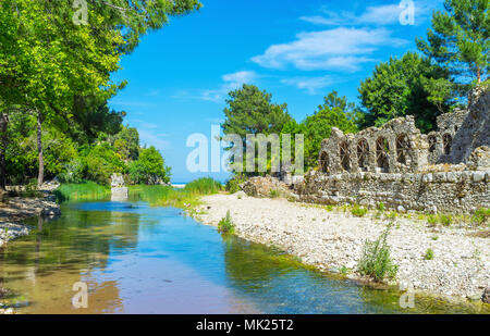 The walk along the narrow Olympos stream with a view on the ancient ruins of Lycian town of Olympos, Turkey. Stock Photo