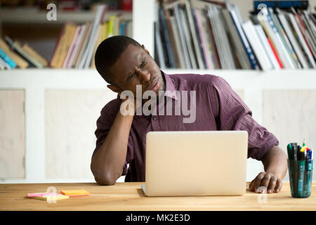Tired African American office worker suffering from neck pain Stock Photo