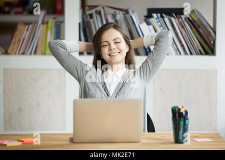 Satisfied female worker leaning in chair happy with company res Stock Photo