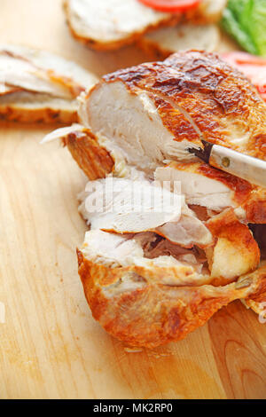 a purchased rotisserie roast chicken with knife on cutting board with room for text Stock Photo