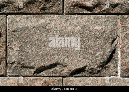 rough granite rectangular block in the composition of masonry wall Stock Photo