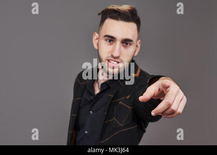Young smiling man in formal wear pointing with finger on you, looking at camera, isolated on gray background Stock Photo
