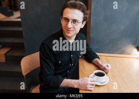 Handsome bearded man in checked shirt holding fork eating in cafe and smiling looking at camera Stock Photo