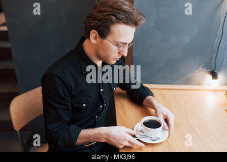 Handsome bearded man in checked shirt holding fork eating in cafe and smiling Stock Photo