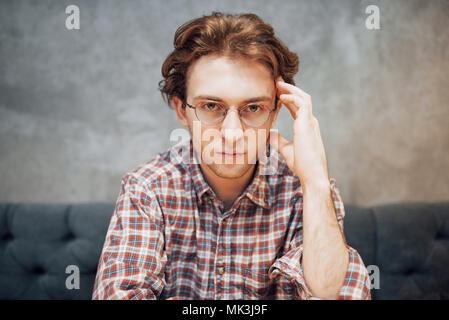 portrait of handsome and relaxed man sitting at a cafe and thinking, working remote, looking on the camera Stock Photo