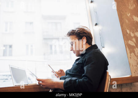 Relaxed young professional surfing the Internet on his laptop in a cafe Stock Photo