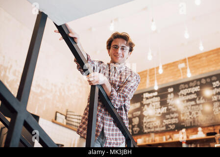 Thoughtful young man is sitting in confectionery shop. She is drinking coffee while waiting for someone Stock Photo