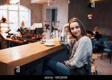 Attractive young woman sitting indoor in urban cafe. Cafe city lifestyle. Casual portrait of teenager girl. Toned. Stock Photo